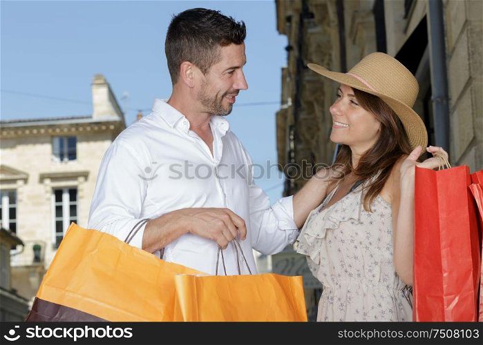 happy smiling couple with bags enjoying shopping