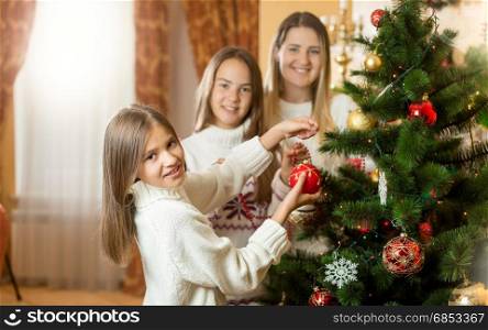 Happy smiling family decorating Christmas tree at living room
