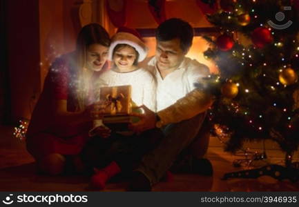 Happy smiling family looking inside of glowing Christmas gift box