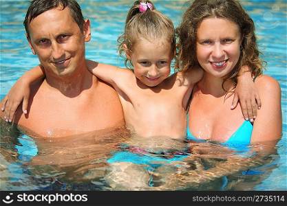 happy smiling family with little girl in water hugging