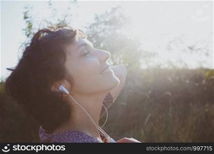 happy smiling girl in headphones listens to music on a sunset background. photo out of focus