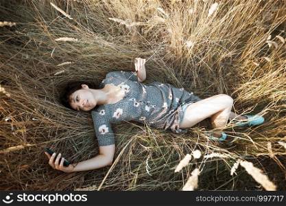 happy smiling girl lies in dry grass and takes a selfie. retro style.