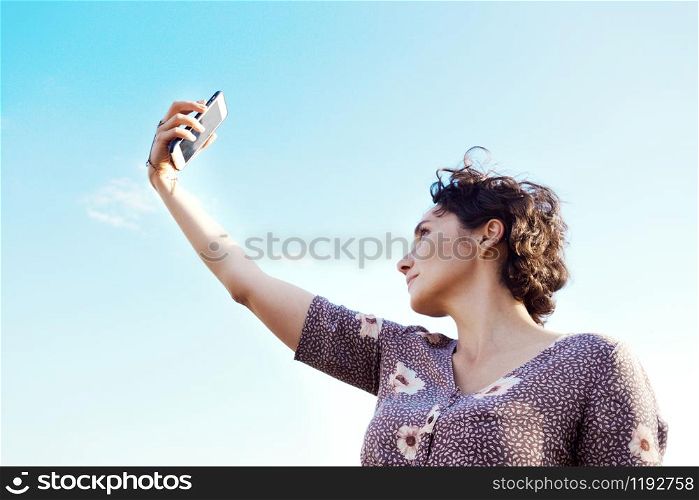 happy smiling girl takes a selfie against the blue sky