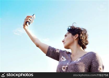 happy smiling girl takes a selfie against the blue sky