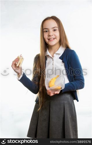 Happy smiling girl taking sandwich out of lunchbox against white background
