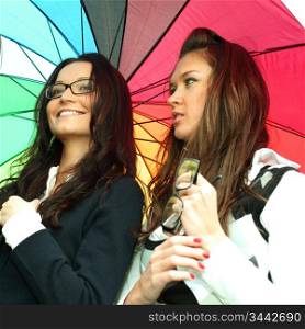 happy smiling girlfriends stay under colourful umbrella