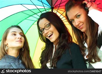 happy smiling girlfriends stay under colourful umbrella