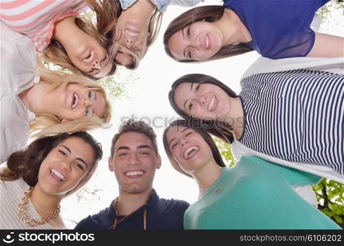 Happy smiling group of young friends staying together outdoor in the park
