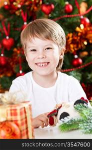 Happy smiling kid against decorated Christmas tree