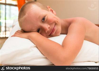 happy smiling little boy lying on a pillow in bed