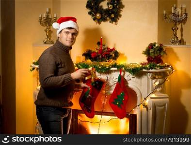 Happy smiling man posing with gift box at decorated fireplace