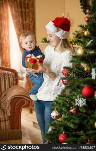 Happy smiling mother and baby boy at Chrsitmas tree
