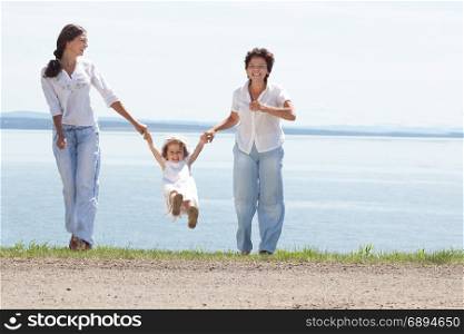 Happy Smiling Mother and Two Daughters Playing Together at the Water View at the Sunny Summer Day