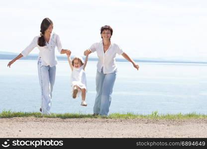 Happy Smiling Mother and Two Daughtesr Playing Together at the Water View at the Sunny Summer Day