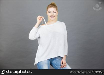 Happy smiling positive woman holding her bra strap from under her sweater. Brafitting concept.. Happy woman holding her bra strap