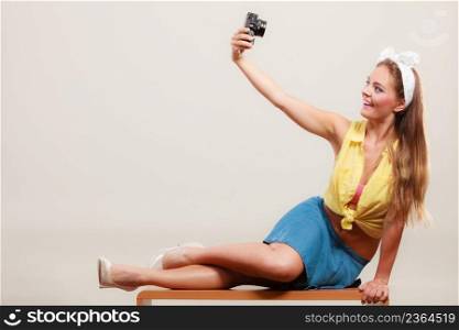 Happy smiling pretty pin up girl wearing hairband bow, skirt and high heels taking photo picture with camera. Attractive gorgeous young retro woman photographing.. Pin up girl woman taking photo with camera.