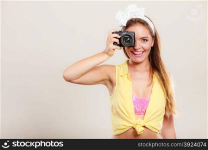 Happy smiling pretty pin up girl with hairband bow taking photo picture with camera. Attractive gorgeous young retro woman photographing.