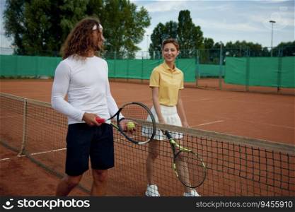 Happy smiling professional tennis player with racket in hands taking rest after training. Sport game and friends competition concept. Happy smiling professional tennis player taking rest after training