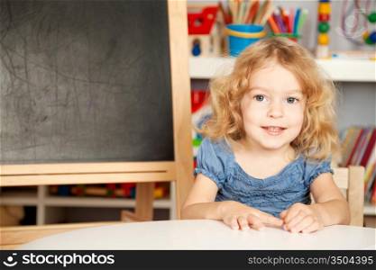 Happy smiling schoolchild in a class against blackboard. School concept
