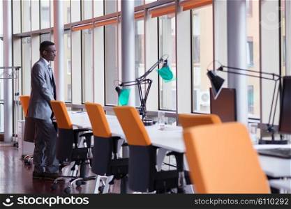 Happy smiling successful African American businessman in a suit in a modern bright office indoors