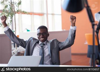 Happy smiling successful African American businessman in a suit in a modern bright office indoors