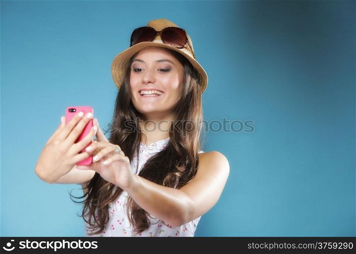 Happy smiling summer girl with smartphone mobile phone reads message or taking photo of herself on blue