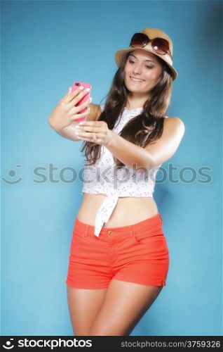 Happy smiling summer girl with smartphone mobile phone reads message or taking photo of herself on blue