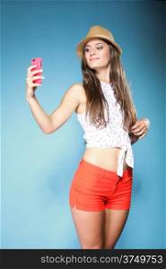 Happy smiling summer girl with smartphone mobile phone taking photo of herself