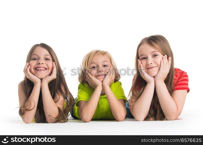 Happy smiling three children in colorful clothes laying on floor isolated on white background. Happy children isolated on white
