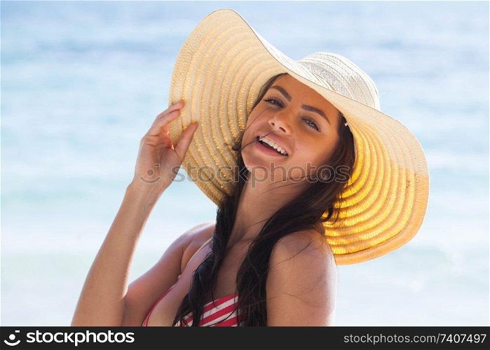 Happy smiling woman in bikini and sunhat on sea beach. Smiling woman in sunhat on sea beach