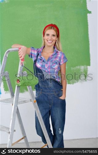 happy smiling woman painting interior white wall in blue and green color of new house