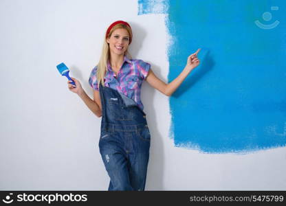 happy smiling woman painting interior white wall in blue and green color of new house