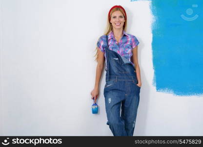 happy smiling woman painting interior white wall in blue and green color of new house