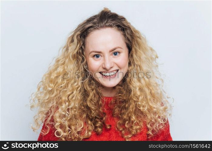 Happy smiling woman with curly luxurious hair, glad expression, satisfied to recieve good news from friend, isolated over white background. People, facial expressions and positive emotions concept.