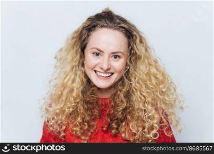 Happy smiling woman with curly luxurious hair, glad expression, satisfied to recieve good news from friend, isolated over white background. People, facial expressions and positive emotions concept.