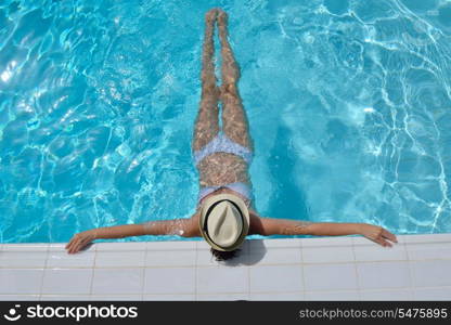 Happy smiling woman with hat and sunglasses in swimming pool at tropical resort