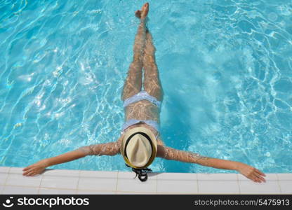 Happy smiling woman with hat and sunglasses in swimming pool at tropical resort