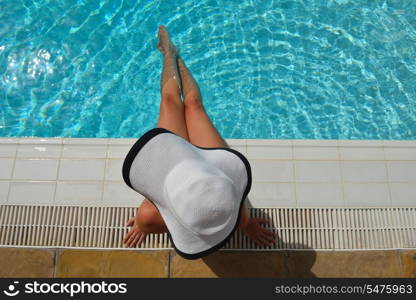 Happy smiling woman with hat and sunglasses in swimming pool at tropical resort