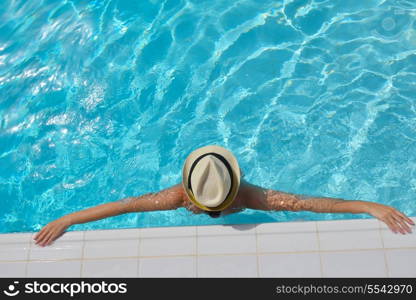 Happy smiling woman with hat and sunglasses in swimming pool at tropical resort