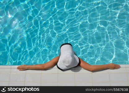 Happy smiling woman with hat and sunglasses in swimming pool at tropical resort