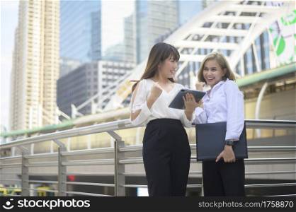 Happy smiling young business women are working in modern city, talking about business plan