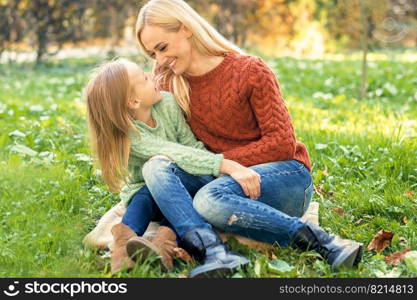 Happy smiling young caucasian mother and little daughter hugging each other outdoors. Happy family outdoor.. Young mother and little daughter hugging each other outdoors.