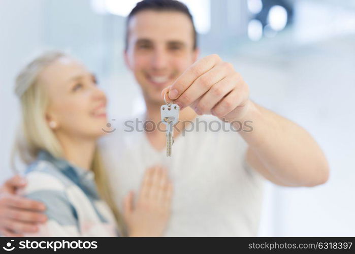 Happy smiling young couple hugging while showing a keys of their new house