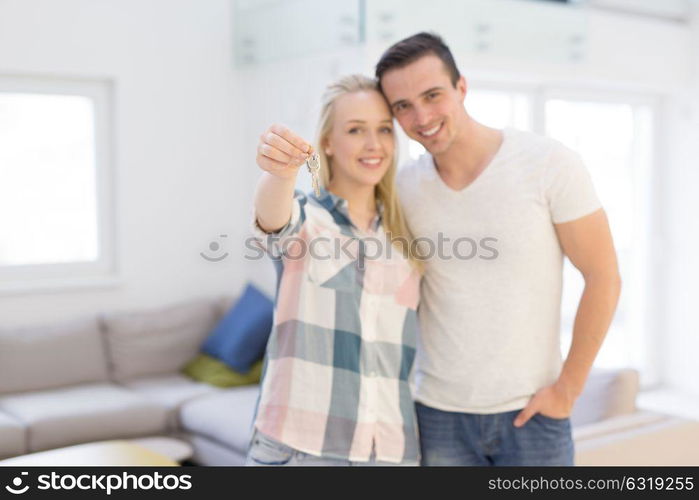 Happy smiling young couple hugging while showing a keys of their new house