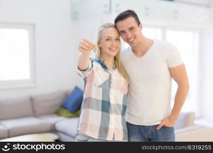 Happy smiling young couple hugging while showing a keys of their new house