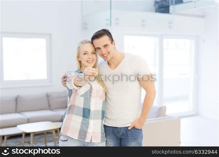Happy smiling young couple hugging while showing a keys of their new house