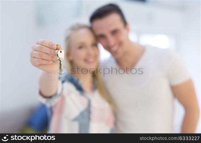 Happy smiling young couple hugging while showing a keys of their new house