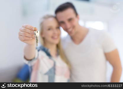 Happy smiling young couple hugging while showing a keys of their new house