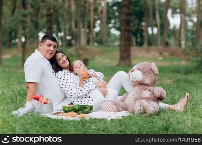 Happy smiling young family on picnic in park at summer day. The concept of summer holiday. Father&rsquo;s, mother&rsquo;s, baby&rsquo;s day. Spending time together. selective focus.. Happy smiling young family on picnic in park at summer day. The concept of summer holiday. Father&rsquo;s, mother&rsquo;s, baby&rsquo;s day. Spending time together. selective focus