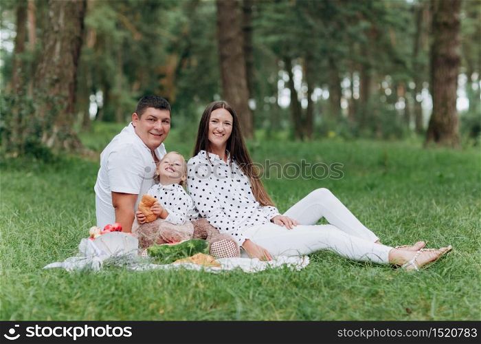 Happy smiling young family on picnic in park at summer day. The concept of summer holiday. Father&rsquo;s, mother&rsquo;s, baby&rsquo;s day. Spending time together. selective focus. Happy smiling young family on picnic in park at summer day. The concept of summer holiday. Father&rsquo;s, mother&rsquo;s, baby&rsquo;s day. Spending time together. selective focus.